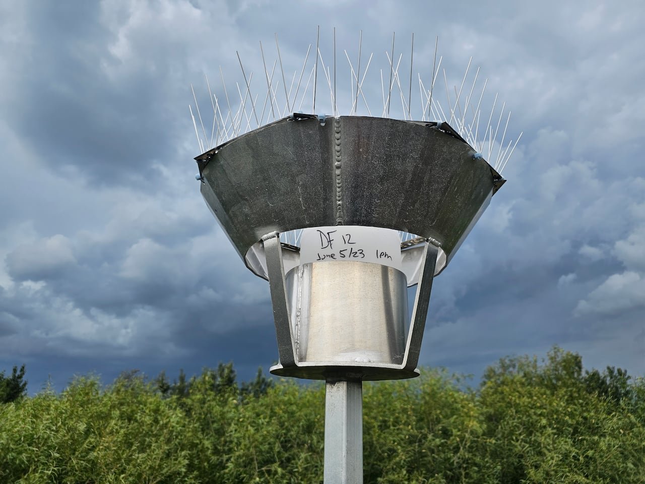 A large bucket sampler covered in spikes sits on a pole